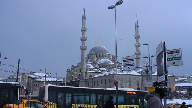 Street traffic and Yeni Mosque in the snow rain. Snow covered Yeni Mosque in Istanbul, Turkey.  A snowy day in Istanbul with the static camera shots