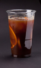 A fresh cold cocktail with coffee and orange slices in a plastic