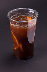 A fresh cold cocktail with coffee and orange slices in a plastic