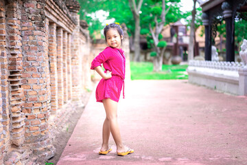 Portrait of happy asian little girl in red dress standing in the park