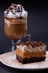 chocolate cake on a white plate with a glass of coffee with a cream and chocotale