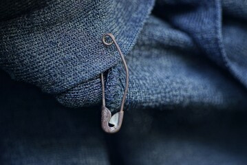 one old metal pin hangs on a gray cloth of clothing