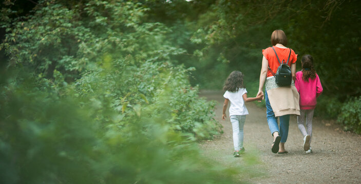 Mother and daughters hiking on path in woods