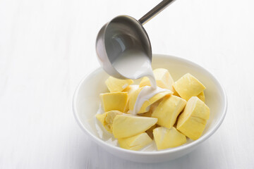 Thai dessert, sliced durian fruit in a bowl eating with coconut milk