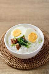 Asian food, Rice soup with boiled egg, grilled mushroom and spinach in a bowl on woven rattan sheet