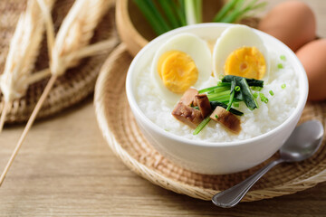 Asian food, Rice soup with boiled egg, grilled mushroom and spinach in a bowl on woven rattan sheet