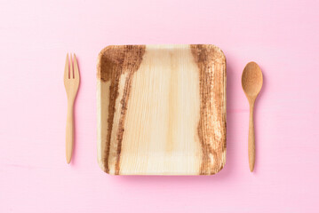 Betel palm leaf plate (Biodegradable plate, Compostable plate or Eco friendly disposable plate) with wooden fork and spoon on pink background