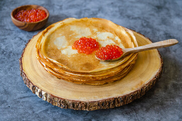 Traditional Russian pancakes with red caviar on a blue background.