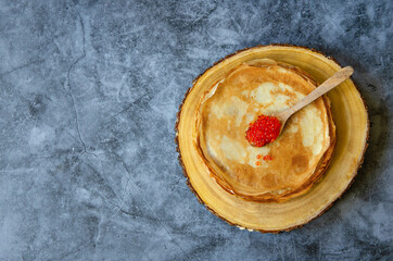 Traditional Russian pancakes with red caviar on a blue background. Space for the text. 