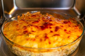 close on round glass dish with food au gratin in microwave oven, short depth of field