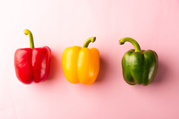 Close up above top view of raw red, yellow and green bell peppers on pink pastel background, fresh organic vegetables, Healthy lifestyle diet food concept