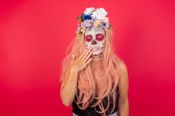 young beautiful woman wearing halloween make up over red background touching mouth with hand with painful expression because of toothache or dental illness on teeth.