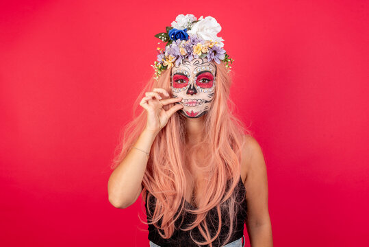 young beautiful woman wearing halloween make up over red background mouth and lips shut as zip with fingers. Secret and silent, taboo talking.