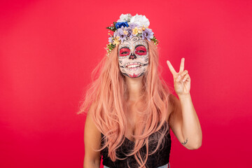 young beautiful woman wearing halloween make up over red background showing and pointing up with fingers number two while smiling confident and happy.