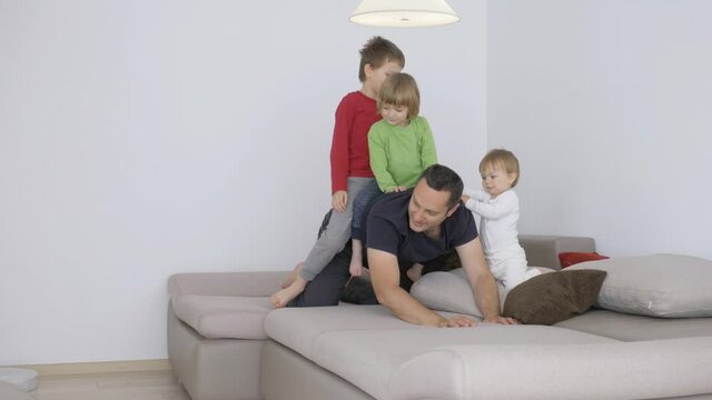 Children ride father back, baby child hold man, family have fun indoor
