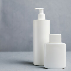White pure plastic cosmetics bottles. Beauty products package on gray background. Body and skin care concept.