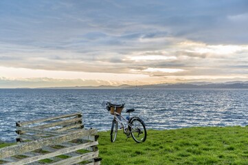 Fototapeta premium Bike parked by wooden fence on a bank above a vast expanse of blue ocean - Esquimalt, Greater Victoria, Vancouver Island, British Columbia, Canada