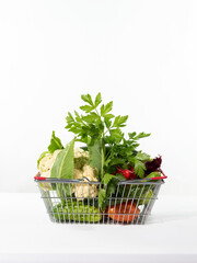 Basket of vegetables on table on white background. Fresh seasonal vegetables in basket.