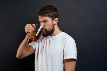 Man with a mug of beer in his hands emotions fun lifestyle white t-shirt dark isolated background