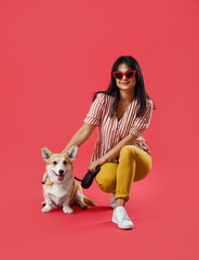 Woman with cute corgi dog on color background