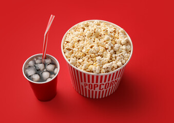 Tasty popcorn and cola on color background
