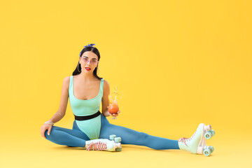 Beautiful young woman on roller skates and with cocktail against color background