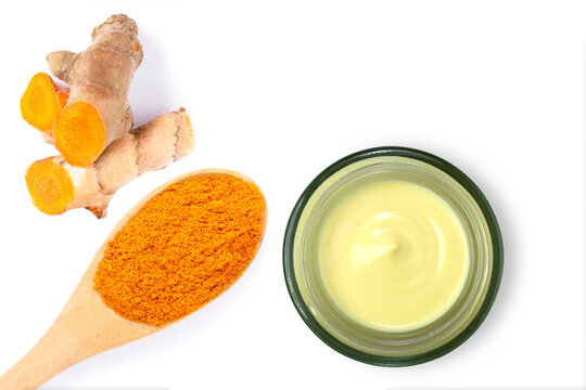 Turmeric Cream In Glass Jar With Tumeric Powder And Root Isolated On White Background. Indian Spice Benefits For Beauty Spa, Natural Face Mask And Skin Care Concept. Copy Space. Top View. Flat Lay.