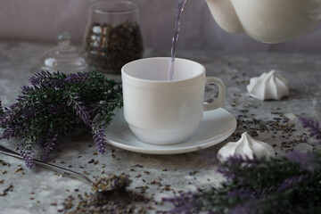 lavender tea in a white mug. Purple tea in a mug on a light background stands on the table next to lavender flowers