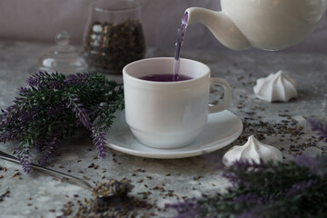 lavender tea in a white mug. Purple tea in a mug on a light background stands on the table next to lavender flowers