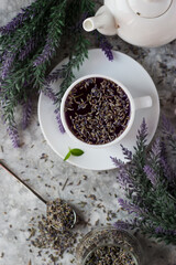 lavender tea in a white mug. Purple tea in a mug on a light background stands on the table next to lavender flowers. Dried lavender flowers are brewed in a Cup.