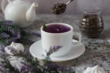 lavender tea in a white mug. Purple tea in a mug on a light background stands on the table next to lavender flowers