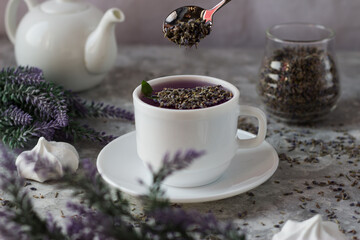 lavender tea in a white mug. Purple tea in a mug on a light background stands on the table next to lavender flowers