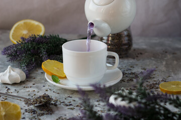 lavender tea in a white mug. Purple tea in a mug on a light background stands on the table next to lavender flowers