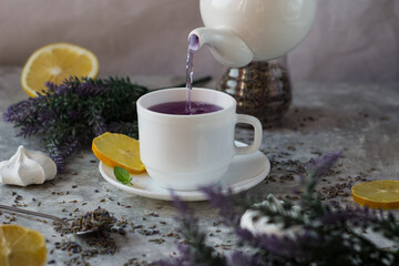 lavender tea in a white mug. Purple tea in a mug on a light background stands on the table next to lavender flowers
