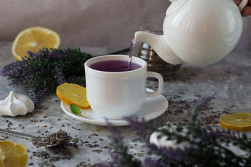 lavender tea in a white mug. Purple tea in a mug on a light background stands on the table next to lavender flowers