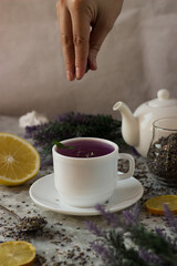 lavender tea in a white mug. Purple tea in a mug on a light background stands on the table next to lavender flowers