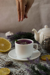lavender tea in a white mug. Purple tea in a mug on a light background stands on the table next to lavender flowers