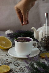 lavender tea in a white mug. Purple tea in a mug on a light background stands on the table next to lavender flowers
