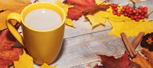 Cup of coffee with milk on a background of yellow leaves. Autumn breakfast concept