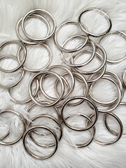 Metal macrame rings are laying on a white faux fur rug.