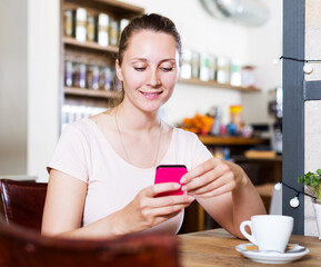 Cheerful young girl ordered coffee and chatting in the phone