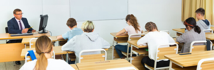 Teen students listening lecture of teacher, smart young people studying at college