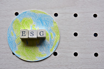 There is the earth and word cube formed "ESG" which are placed on a puching board.