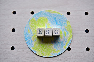 There is the earth and word cube formed "ESG" which are placed on a puching board. © hogehoge511