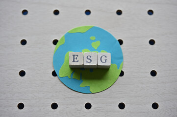 There is the earth and word cube formed "ESG" which are placed on a puching board. © hogehoge511