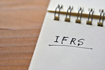 At the edge of the notebook, "IFRS" is written. Close-up.