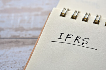 At the edge of the notebook, "IFRS" is written. Close-up.