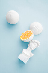 citrus orange painted white with small bust on baby blue background 