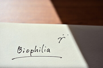 At the edge of the notebook, "Biophilia" is written. Close-up in direct sunlight.