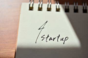At the edge of the notebook, "Startup" is written. Close-up.